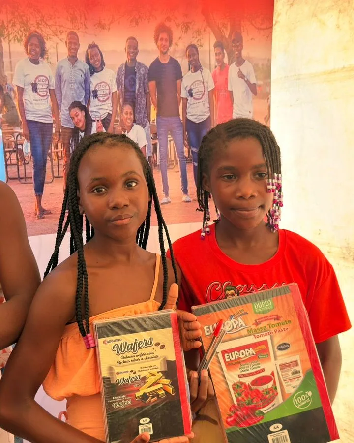 Girls supported by Associação Jovem Activo holding their new school materials