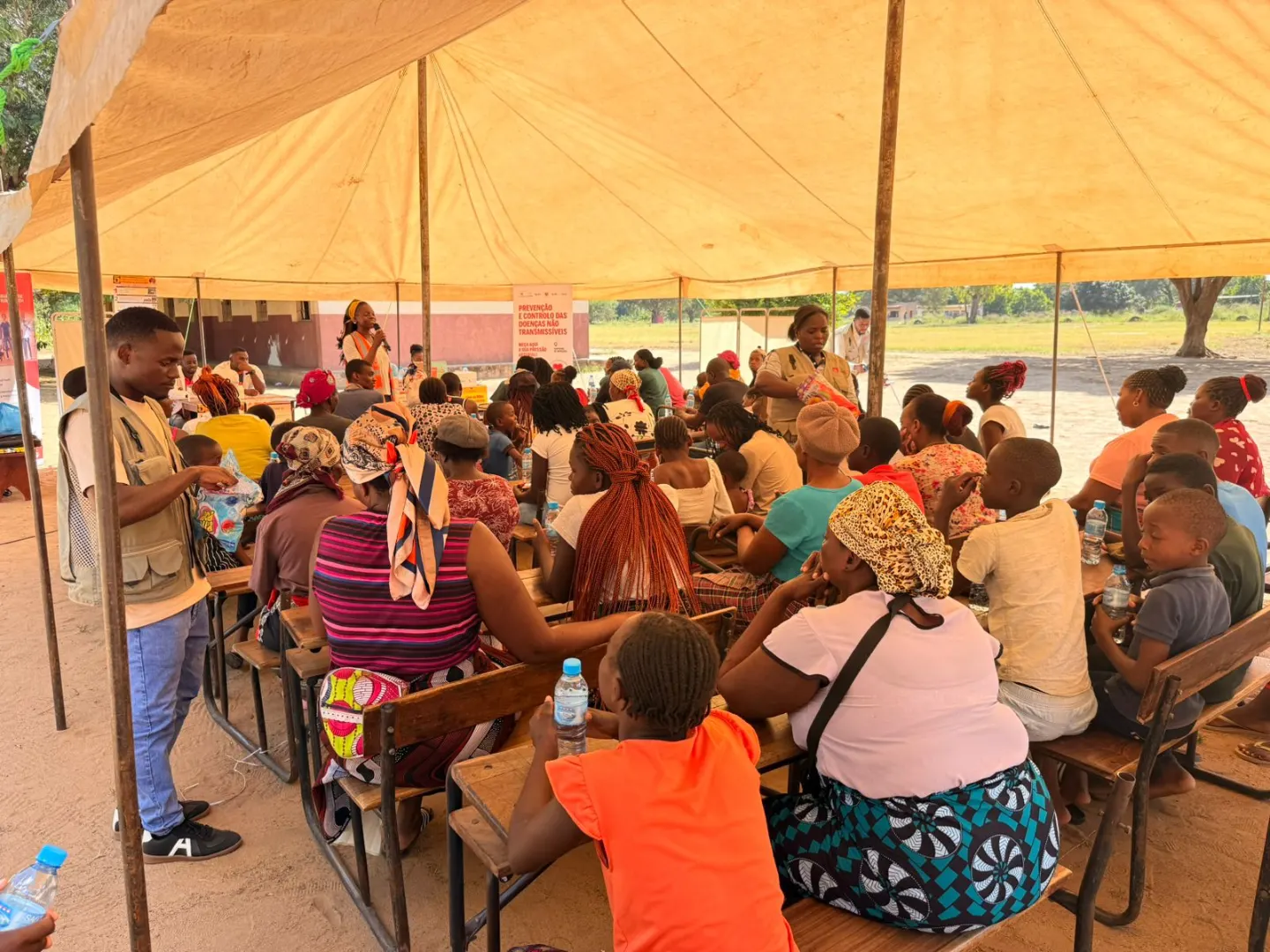 Community awareness session under a tent in Sabié